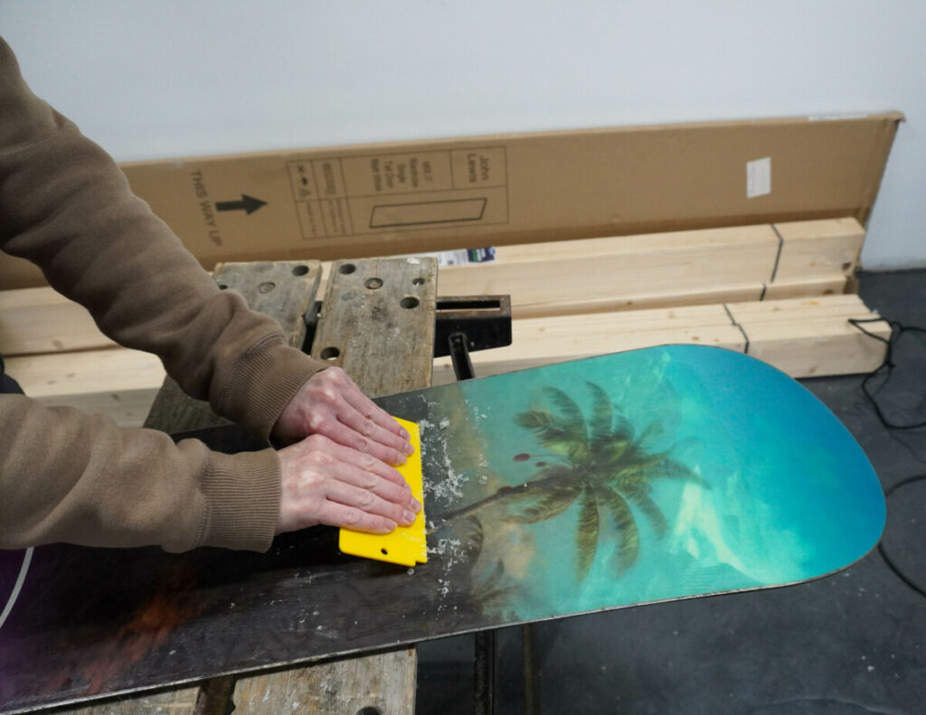 Scraping wax off a snowboard